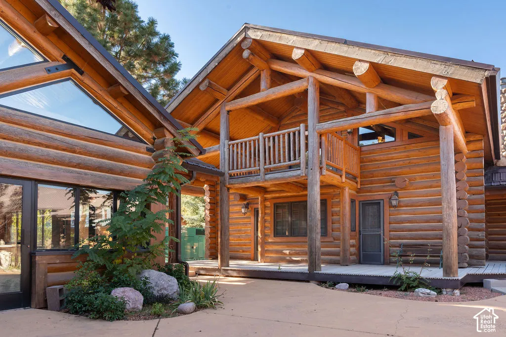 Log exterior architecture featuring exposed timber framing, a covered porch, and a second-story balcony with wooden railing