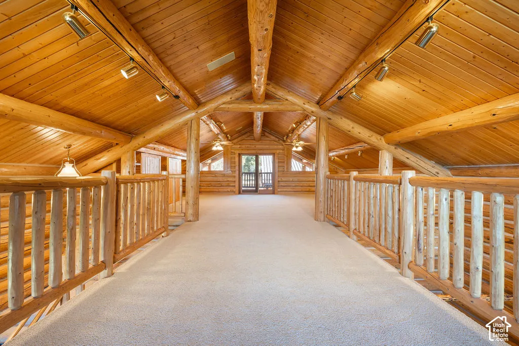 Private loft above primary bedroom with vaulted ceilings with exposed log trusses, wood paneling, log railing system, adjustable track lighting, and two private balconies.