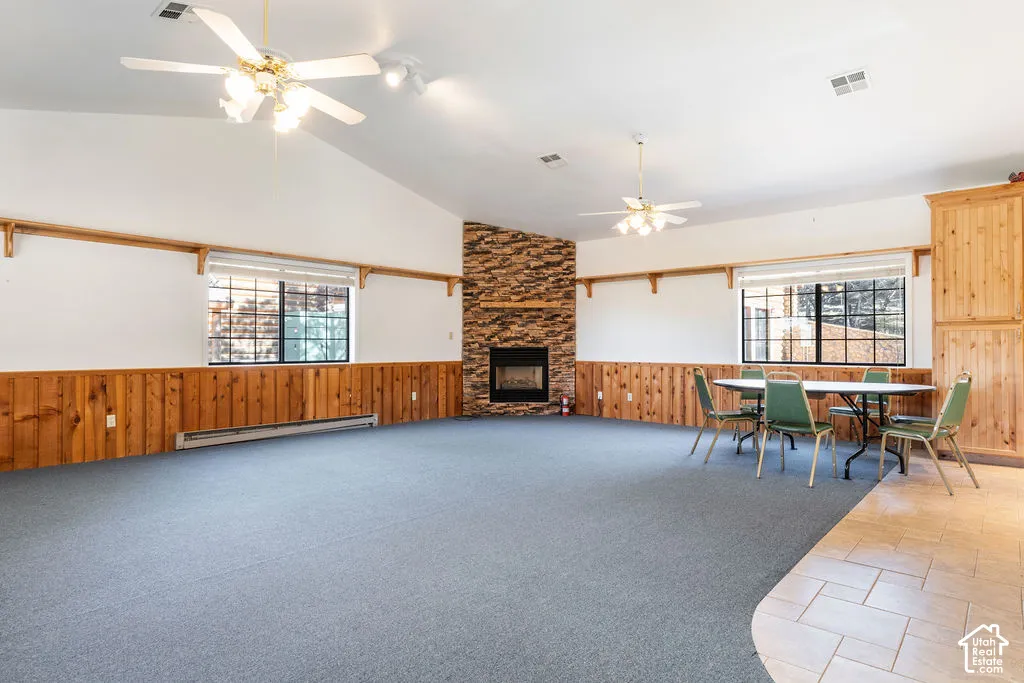 Detached guest house features vaulted ceilings with dual ceiling fans, floor-to-ceiling stone fireplace, and wood wall paneling