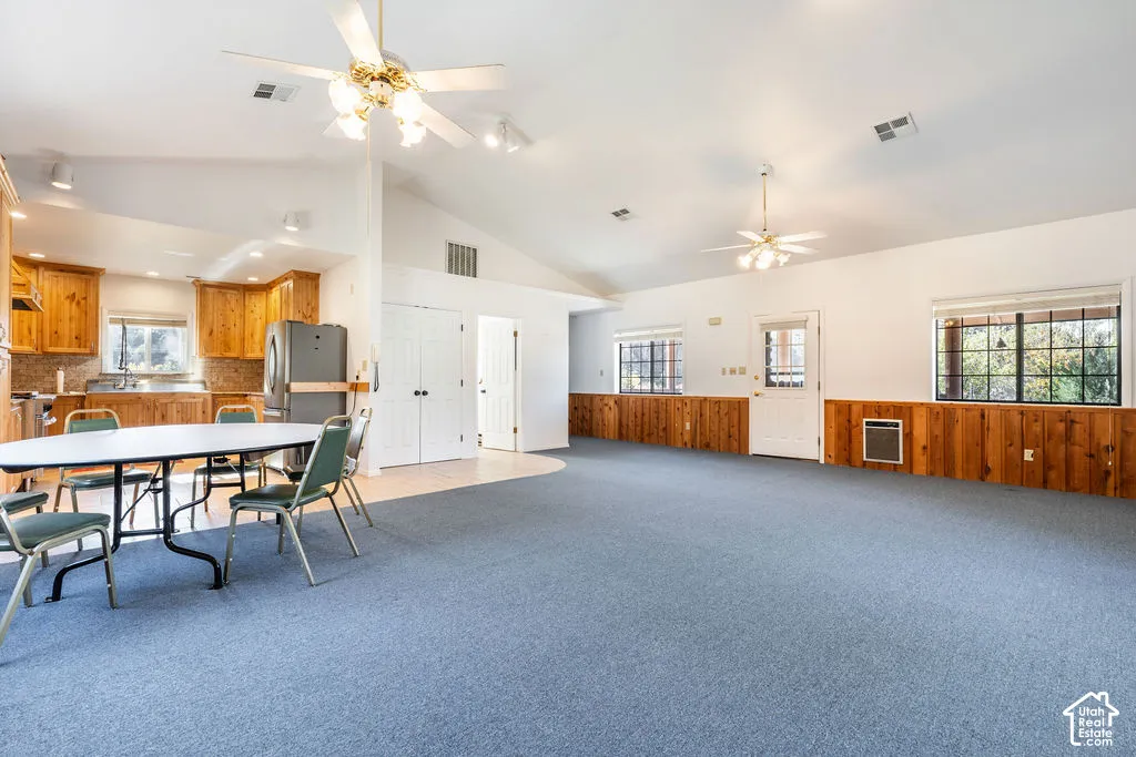 Detached guest house with vaulted ceilings, wood-paneled lower wall finishes, dual ceiling fans, and multi-paned windows