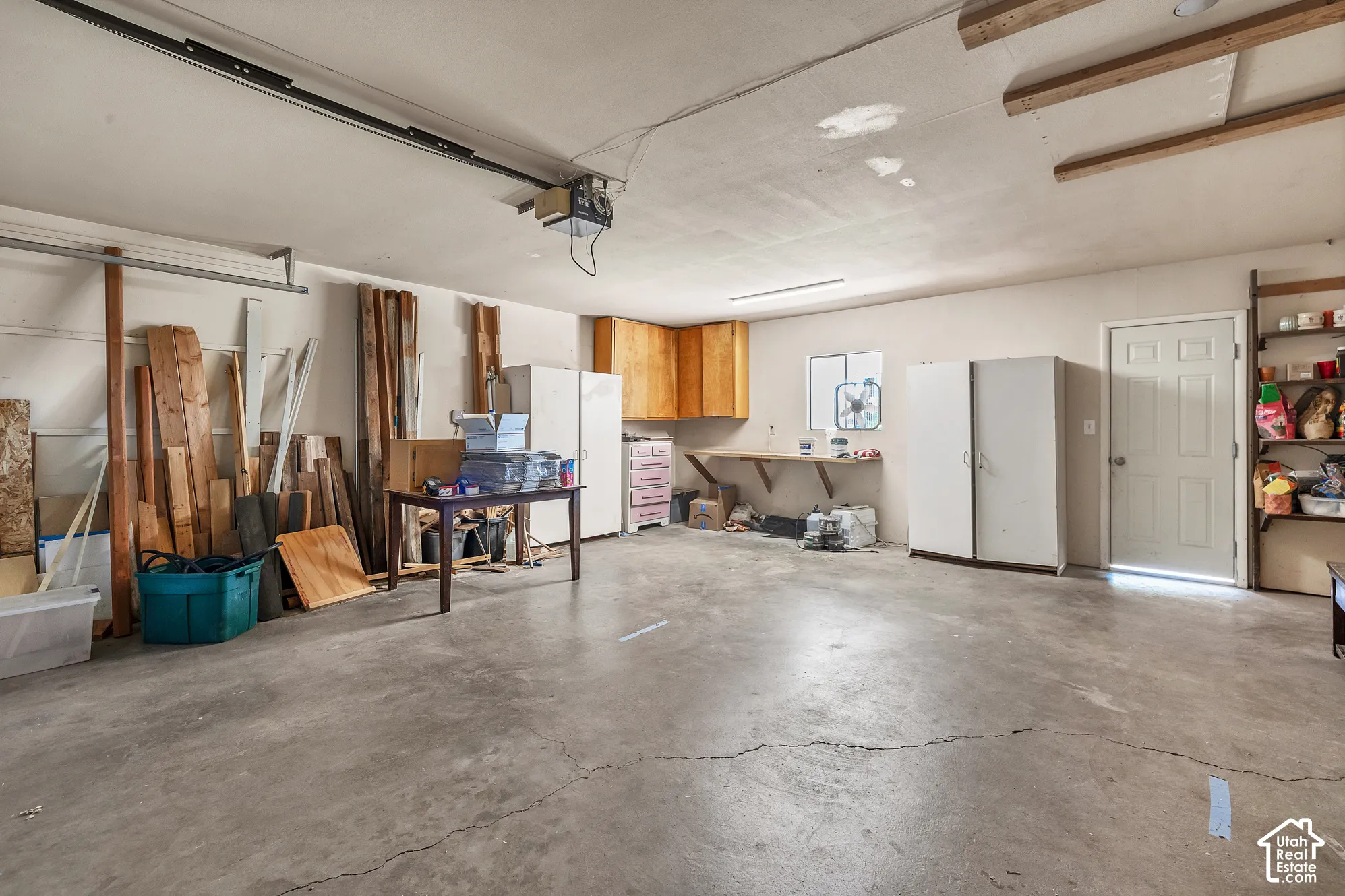 Attached garage featuring concrete flooring, built-in wooden cabinetry, a wall-mounted workbench, and a dedicated entry door