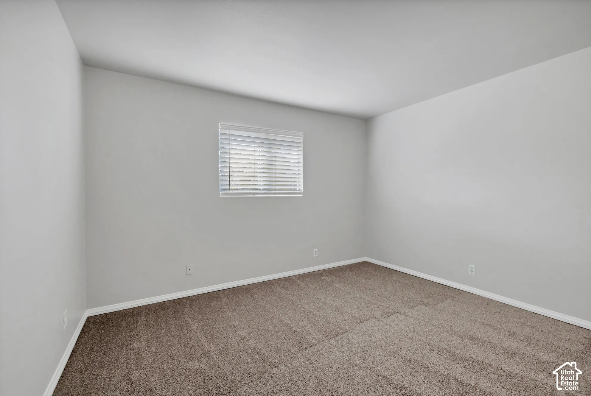 Neutral interior space featuring carpeting and a window with installed blinds