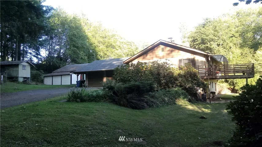 Very private home, viewing left with 2 car garage, carport, Shop, and multi-use building. Deck with view of creek on right.