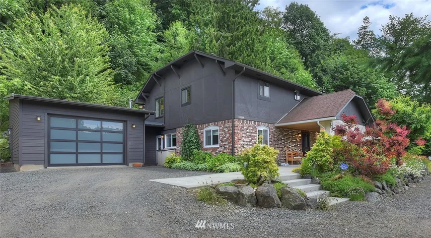 This charming home is nestled against an evergreen backdrop and welcomes you to a unique lifestyle on this gorgeous 4.5 acres. Note the windowed garage door. Translucent glass lights up the interior space during the day.