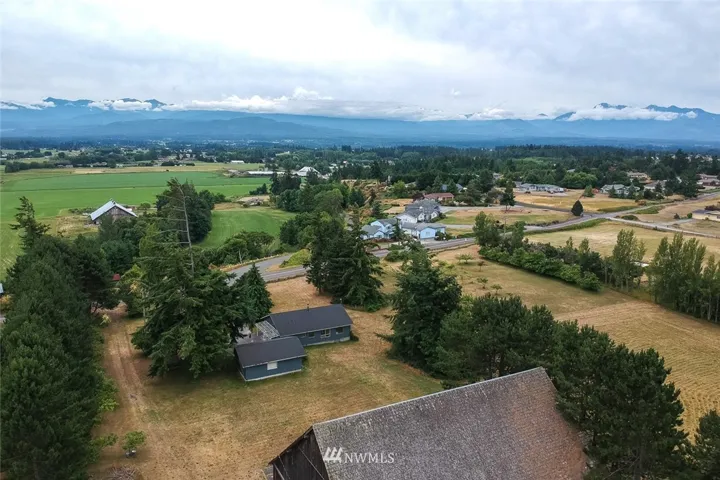 Viewing south across barn and farmhouse and garage in foreground.  Orchard is in center right of photo.
