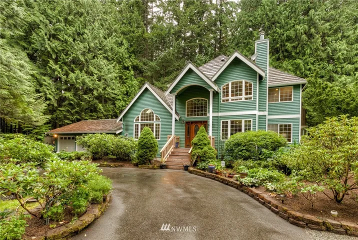 Front of the home from the circular driveway. Brand new front porch with new columns, trex deck flooring. Metal roof over the main part of the home; new roof over the garage (not in picture). Beautiful private setting; feels like you are getting away from it all!