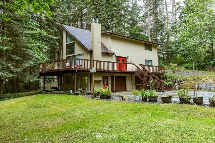 Tucked away with privacy, a wrapped around deck, 3 car garage, paved driveway, a little peekaboo view of water, with potential to clear more trees for a bigger view.