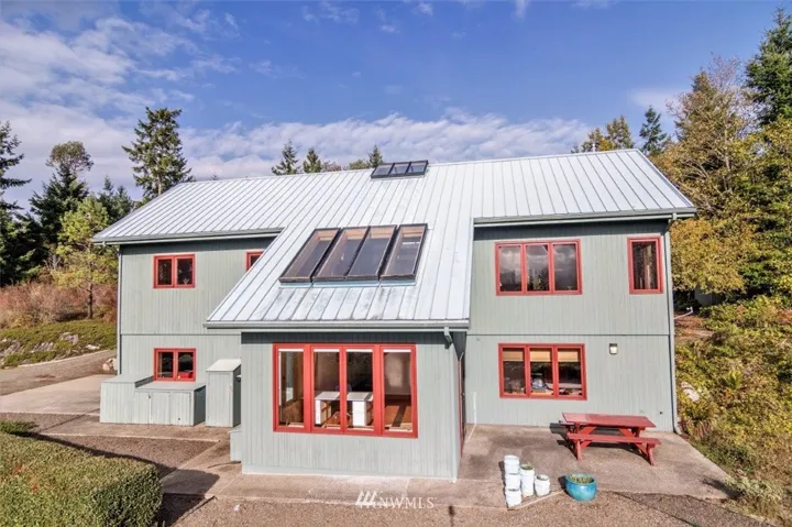Fantastic energy efficient home with metal roof. This view shows the back of the home. Upper level has the main living quarters, allowing the most possible sunlight into the house, through skylights and windows.