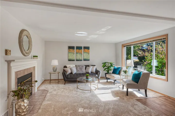 Bright sun filled living room with wood burning fireplace & new carpeting