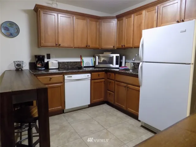 Kitchen with granite counters, 2 burner cooktop, full-size dishwasher and refrigerator.  Beautiful cabinets!
