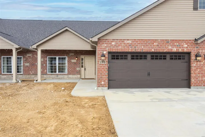Ranch-style house featuring a garage, brick siding, roof with shingles, and driveway
