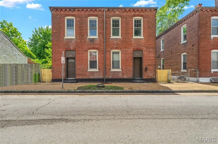 View of front of home with brick siding and fence