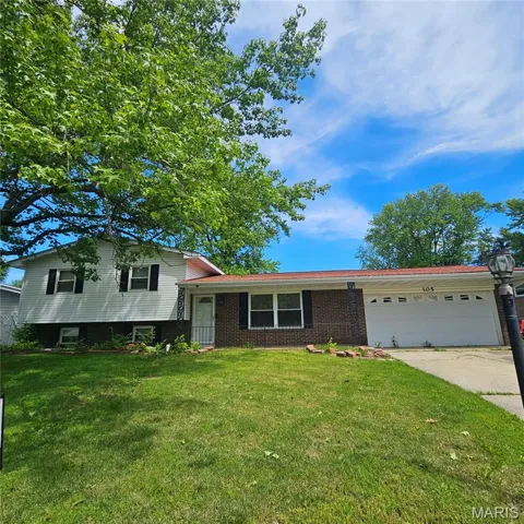Split level home featuring an attached garage, a front lawn, driveway, and brick siding