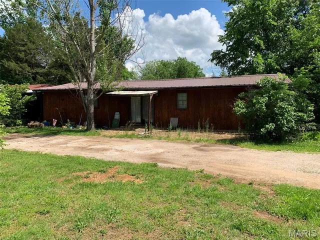 View of front of house featuring metal roof and dirt driveway