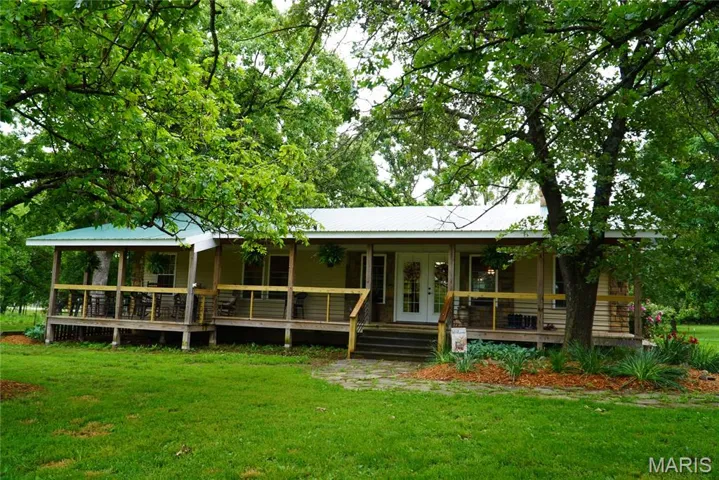 View of front of property featuring covered porch, a front lawn, and metal roof