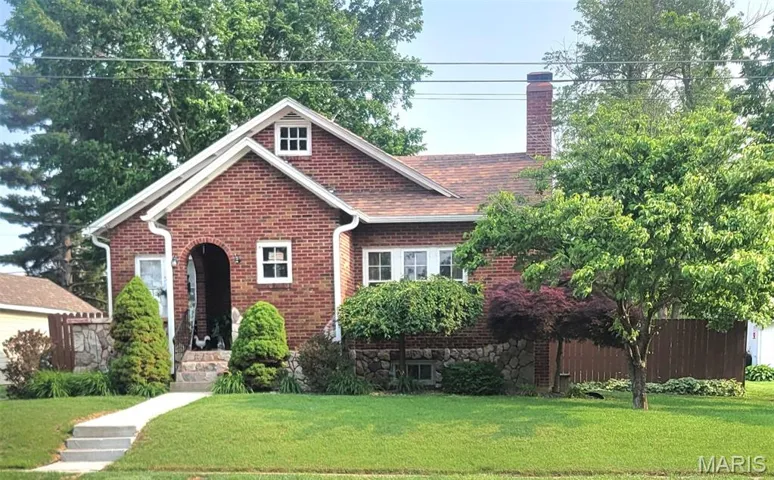 View of front of house with brick siding, a front yard, and a chimney