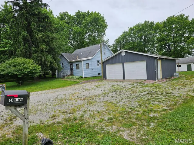 View of front of house with a detached garage, an outdoor structure, and a front yard