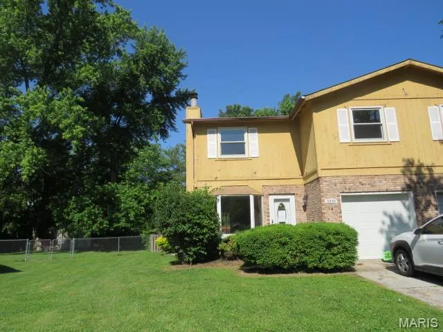 View of front of property with a chimney, a garage, and brick siding