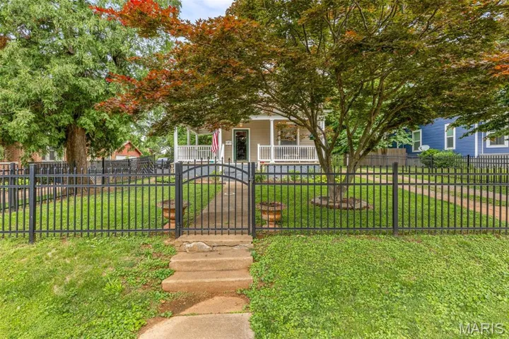 View of property hidden behind natural elements featuring a porch and a gate