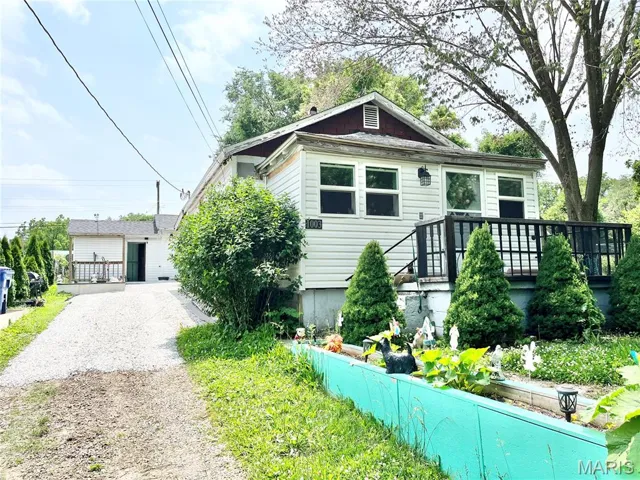 View of front of house featuring gravel driveway and a deck