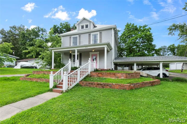 Traditional style home with a porch, a front yard, and a carport