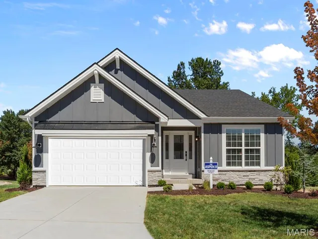 Single story home featuring board and batten siding, stone siding, driveway, an attached garage, and a front lawn
