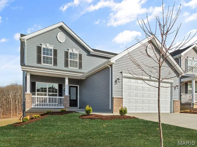 View of front of house with a porch, brick siding, driveway, an attached garage, and a front yard