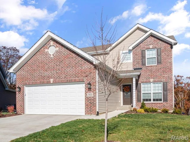 Traditional-style house with brick siding, driveway, a front yard, and a garage