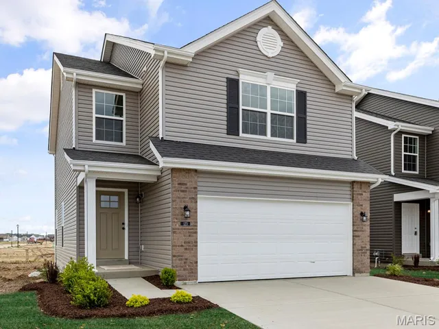 View of front of home with an attached garage, concrete driveway, and brick siding