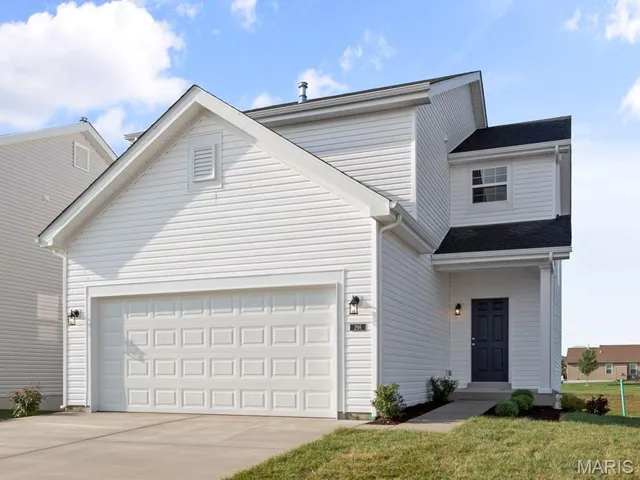 Traditional-style home with concrete driveway, an attached garage, and a front yard