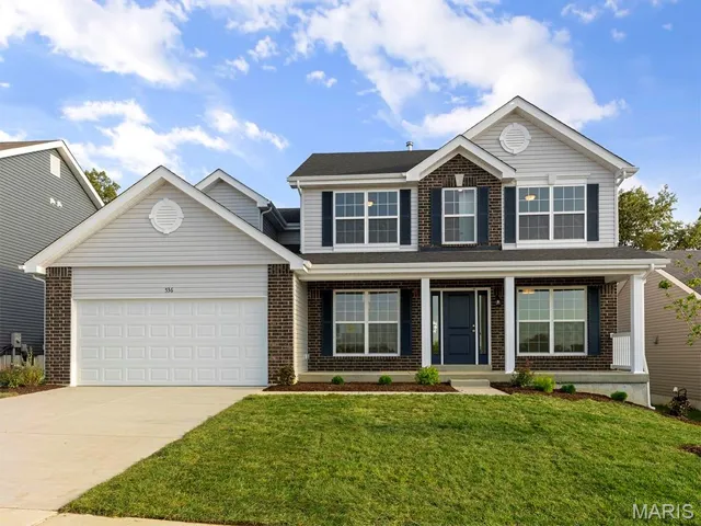 Traditional home with brick siding, driveway, a garage, and a front lawn