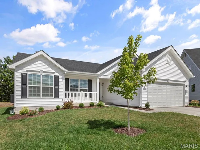 Single story home featuring a porch, a garage, driveway, a front yard, and roof with shingles