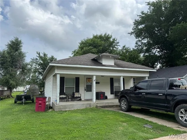 Bungalow-style home with covered porch, a front lawn, and a shingled roof