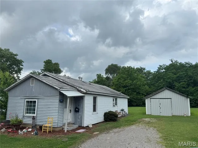 View of front of house featuring a front yard, driveway, and an outbuilding