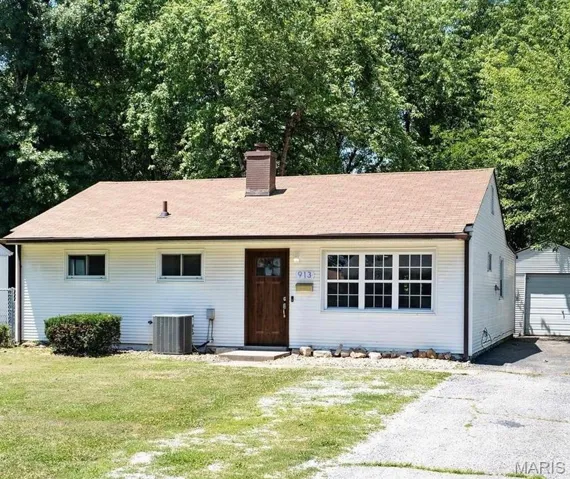 Ranch-style house featuring an outdoor structure, a chimney, a front lawn, a detached garage, and asphalt driveway