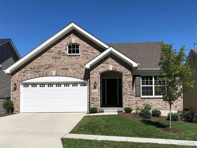 View of front of property with driveway, a front yard, brick siding, an attached garage, and a shingled roof