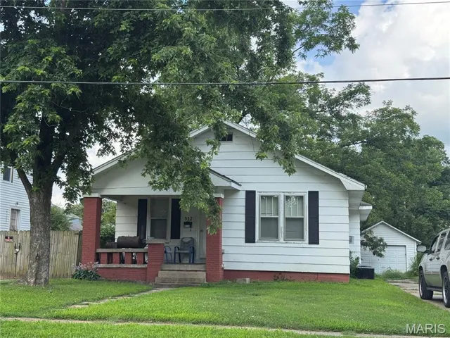Bungalow-style home featuring a porch and a detached garage