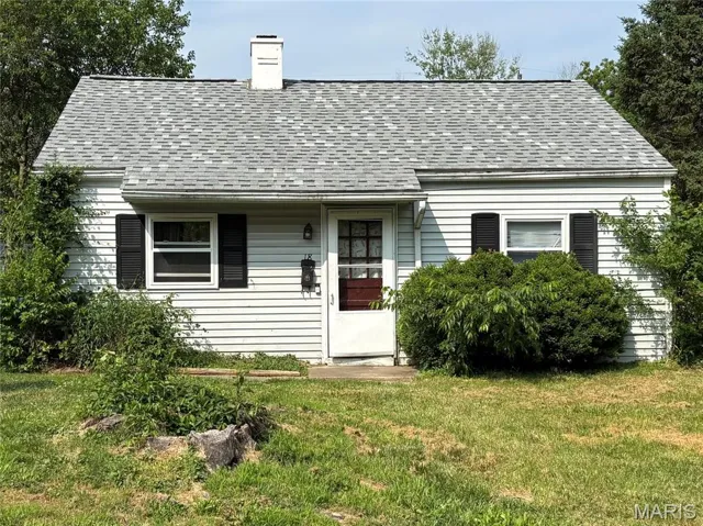 View of front of home featuring a chimney, roof with shingles, and a front lawn