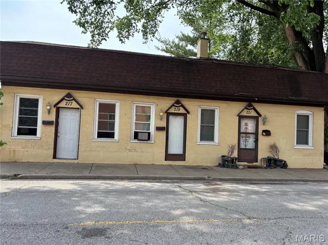 View of front of home with roof with shingles, a chimney, and brick siding