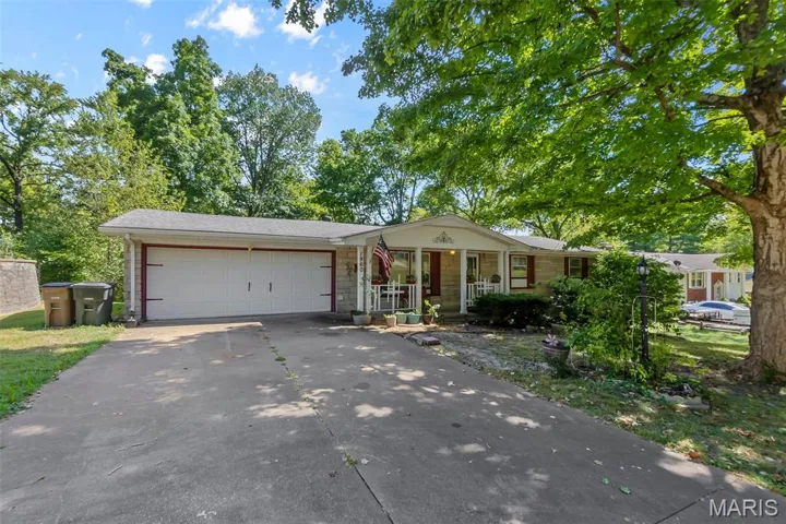Ranch-style house featuring a porch, concrete driveway, and a garage