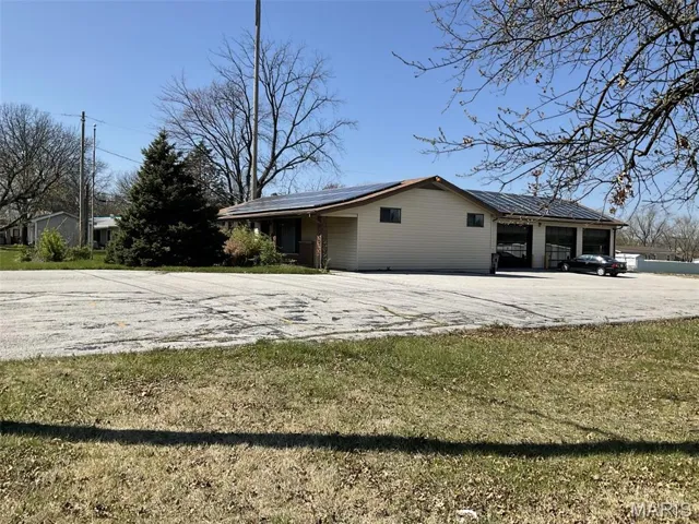 View of side of property with a yard, a garage, and concrete driveway