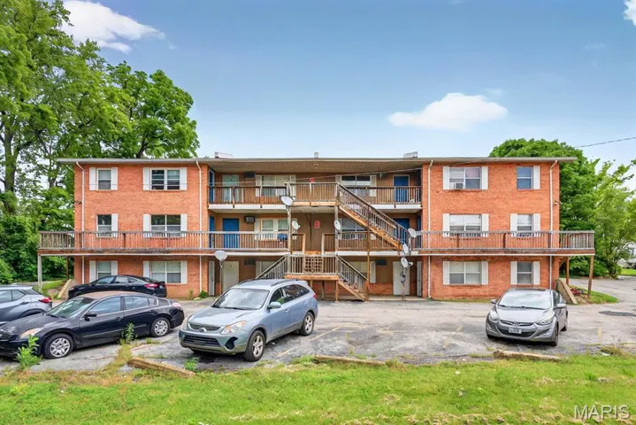 View of apartment building / complex featuring uncovered parking and stairs
