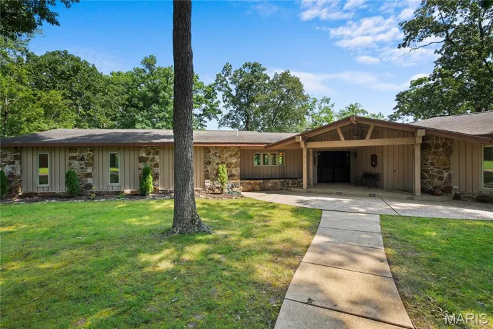 Mid-century inspired home featuring stone siding, a front yard, a shingled roof, and board and batten siding