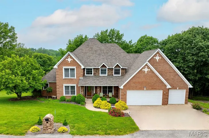 Traditional-style home with a shingled roof, a front lawn, brick siding, concrete driveway, and covered porch
