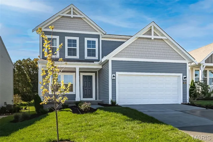 View of front facade with a front lawn, driveway, a garage, and a porch