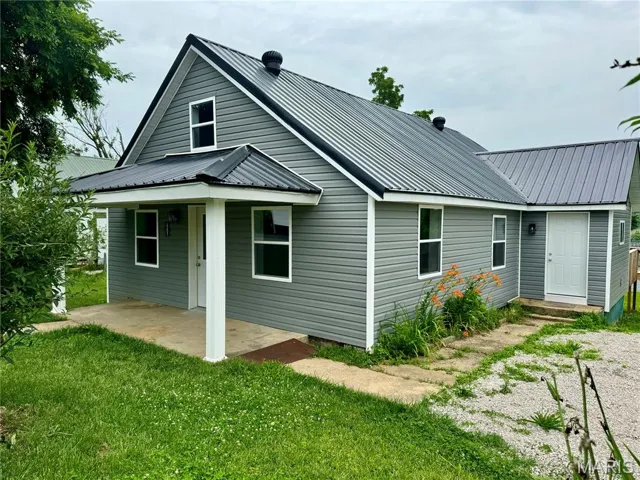 Rear view of property featuring a yard, a metal roof, and a patio