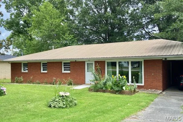 Ranch-style home featuring a front yard, brick siding, and asphalt driveway
