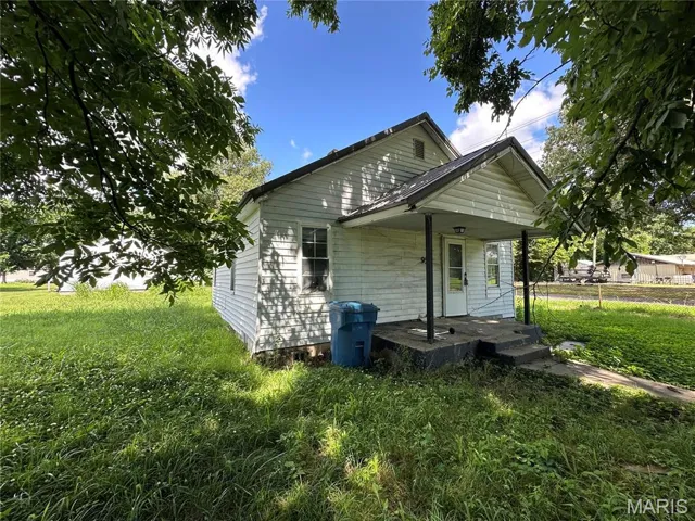 Back of property featuring a lawn and covered porch