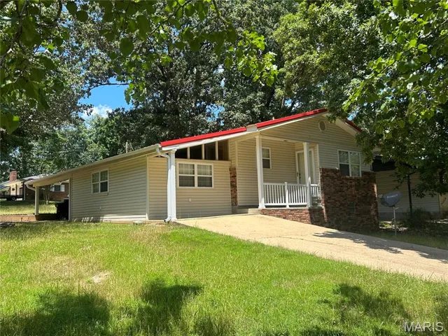 View of front of home featuring concrete driveway, a front lawn, and covered porch
