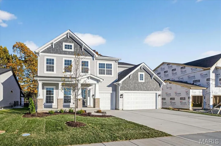 View of front of property with concrete driveway, a front lawn, a porch, and an attached garage